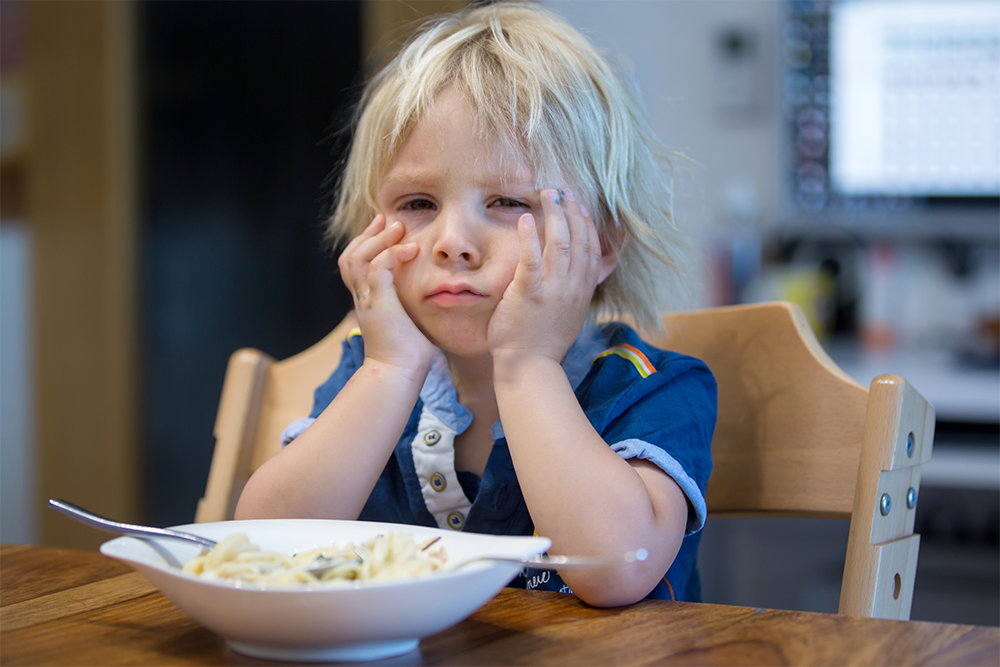 por que meu filho não come – intelecta criança emburrada de frente a um prato de comida