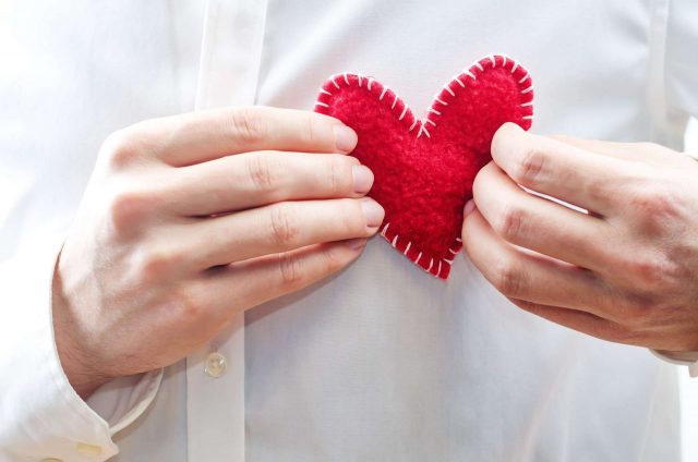 The man in the white shirt is holding a toy heart